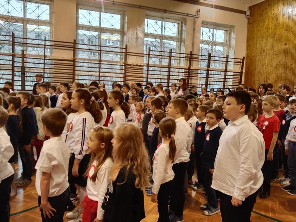 uczniowie śpiewający pieśni patriotyczne podczas apelu